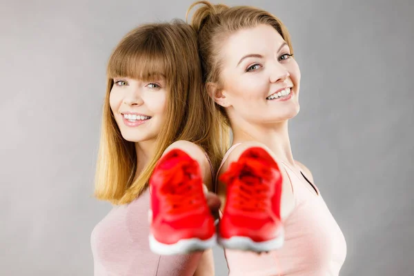 Dos mujeres presentando zapatillas deportivas zapatillas — Foto de Stock