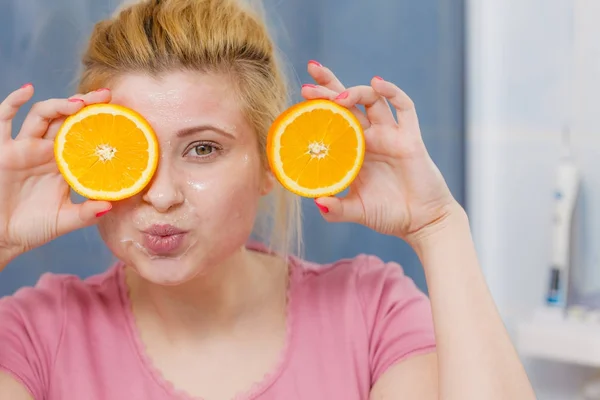 Woman having gel mask on face holding orange — Stock Photo, Image