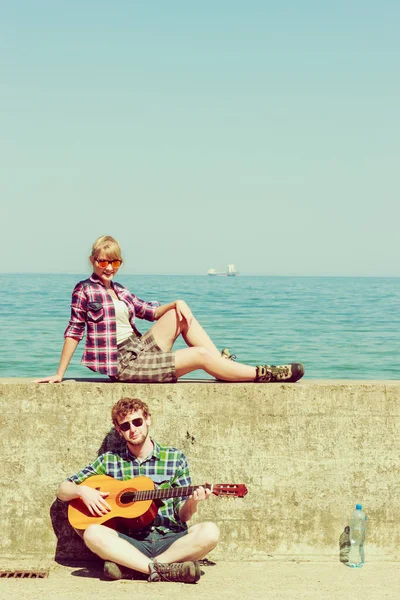 Genç adam onun kız arkadaşı deniz kenarında gitar çalmak — Stok fotoğraf