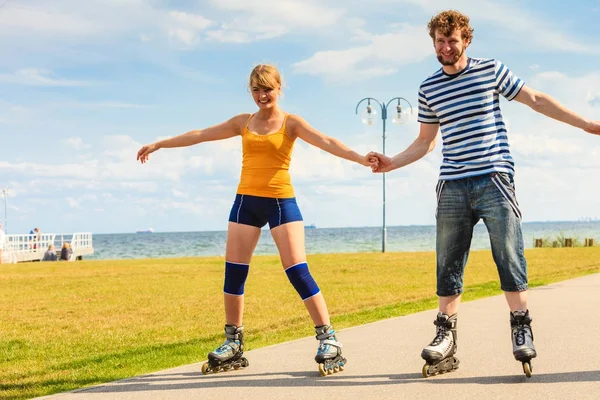 Pareja joven en patines de ruedas montando al aire libre — Foto de Stock