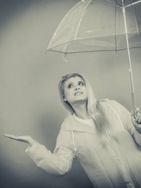 Hava kontrol şemsiye tutan yağmurluk giyen kadın