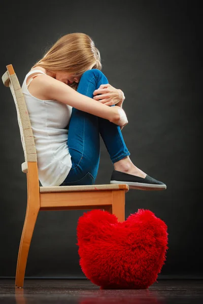 Surullinen onneton nainen punaisella sydäntyynyllä — kuvapankkivalokuva