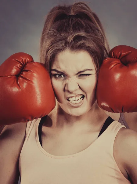 Woman having head between boxing gloves
