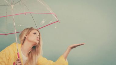 Hava kontrol şemsiye tutan yağmurluk giyen kadın
