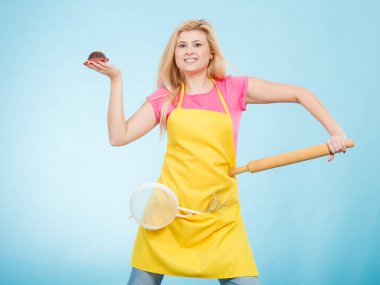 Tutan cupcake, oklava, kevgir önlük giyen kadın