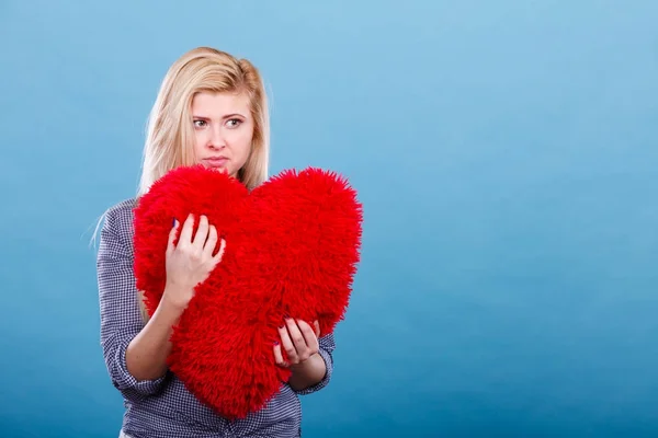 Traurige Frau mit rotem Kissen in Herzform — Stockfoto