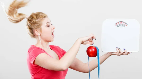 Woman holding apple,measuring tape and weight machine — Stock Photo, Image