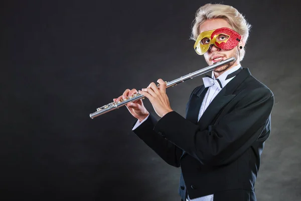 Homem em máscara de carnaval tocando flauta — Fotografia de Stock