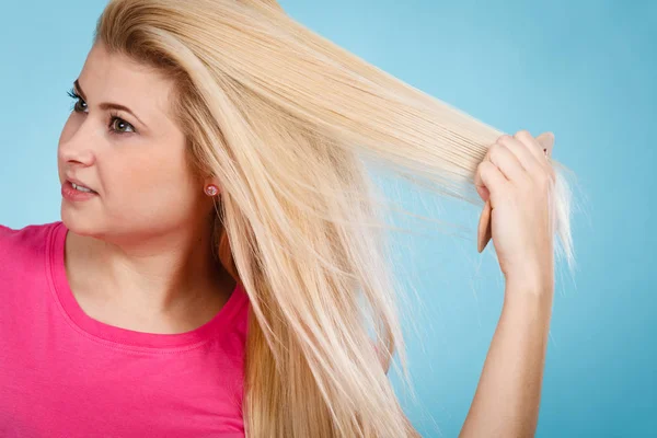 Kvinna borsta hennes långa blonda hår med kam — Stockfoto