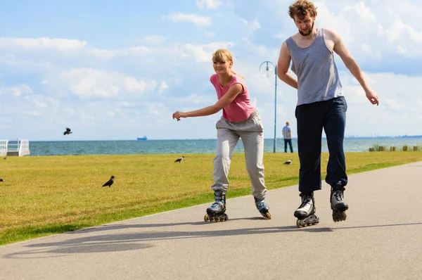 Jonge paar rijden rollerblades in park. — Stockfoto