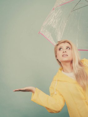 Hava kontrol şemsiye tutan yağmurluk giyen kadın