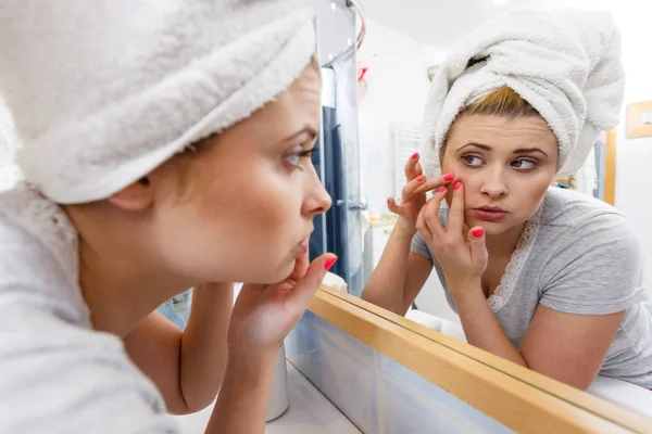 Mujer mirando en el espejo tratando con el acné — Foto de Stock