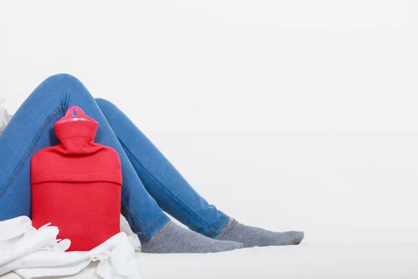 Femme couchée sur le canapé avec une bouteille d'eau chaude — Photo