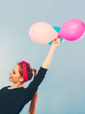 Tatlı gülümseyen kız renkli balonlar tutar.