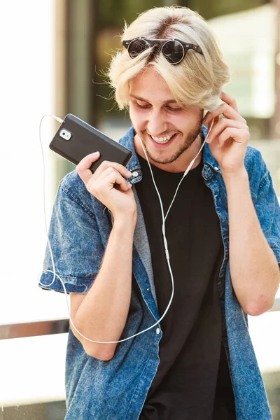 Hipster man standing with earphones talking on phone — Stock Photo, Image