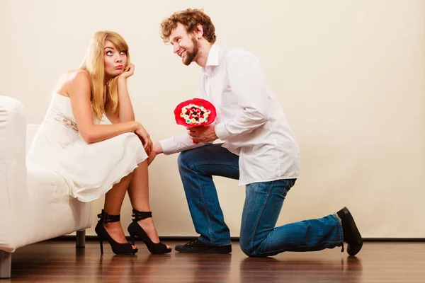 Homem dando infeliz mulher doce cacho flores . — Fotografia de Stock