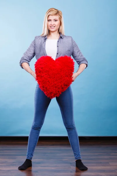 Femme heureuse tenant oreiller rouge en forme de coeur — Photo