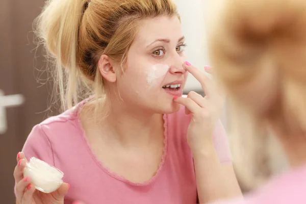 Mujer aplicando crema facial con el dedo — Foto de Stock