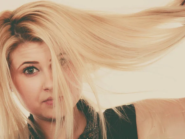 Blonde woman holding her dry hair