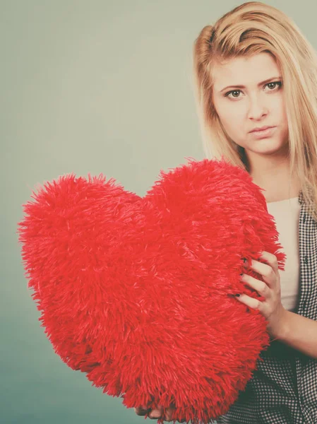 Mujer triste sosteniendo almohada roja en forma de corazón — Foto de Stock