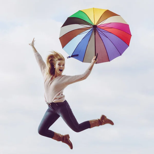 Funny woman jumping with umbrella