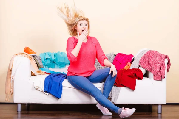 Vrouw weet niet wat te dragen zittend op bank — Stockfoto