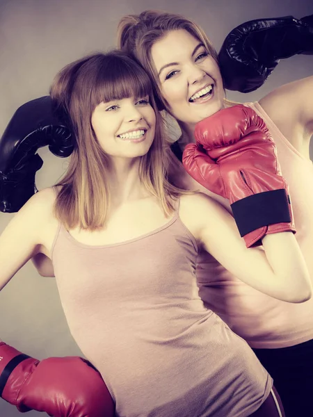 Two women friends wearing boxing gloves