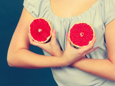 Kadın greyfurt narenciye meyve meme üzerinde tutar