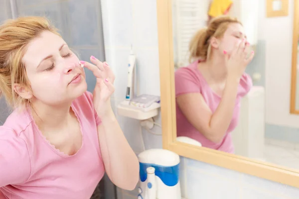 Mulher aplicando creme facial com o dedo — Fotografia de Stock