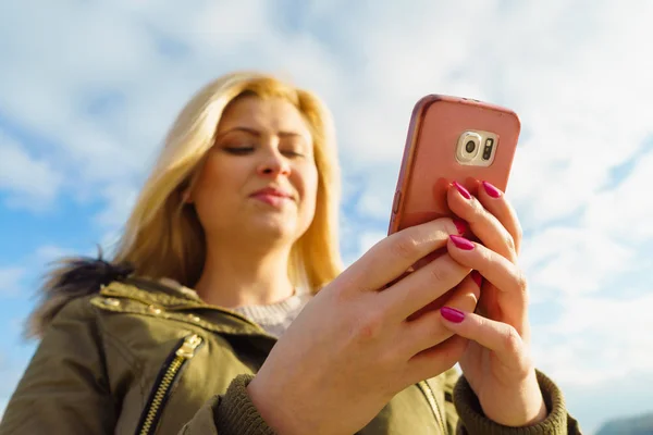 Frau benutzt ihr Smartphone draußen, sonniger Tag — Stockfoto
