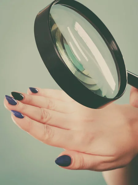 Femme regardant les ongles à travers la loupe — Photo