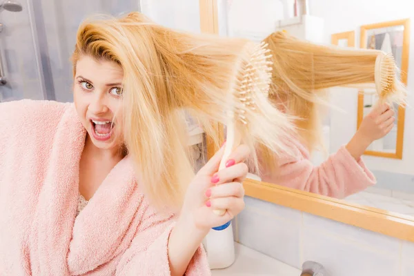 Mujer conmocionada usando bata cepillándose el pelo — Foto de Stock