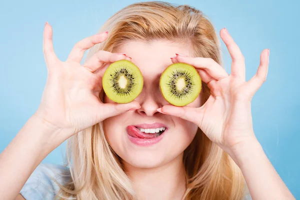 Woman holding green kiwi fruit like eyeglasses — Stock Photo, Image