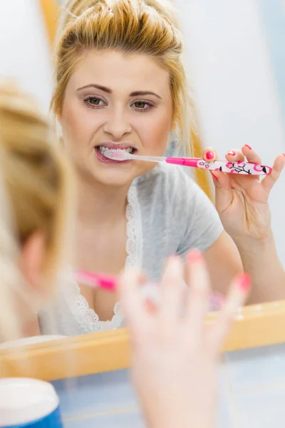 Mulher escovando os dentes de limpeza no banheiro — Fotografia de Stock