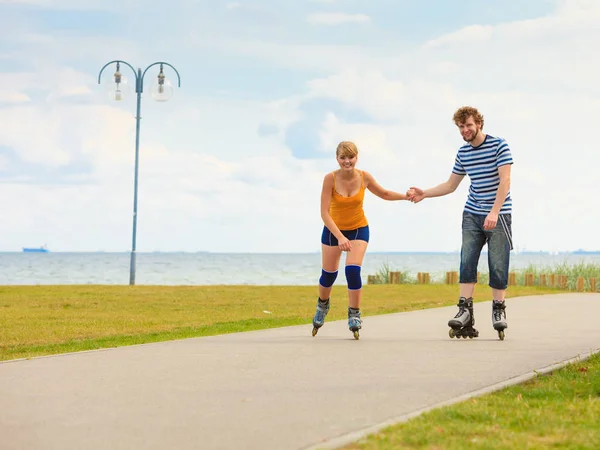 Pareja joven en patines de ruedas montando al aire libre — Foto de Stock