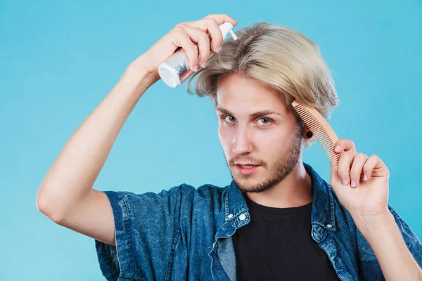 Man applying spray cosmetic to his hair