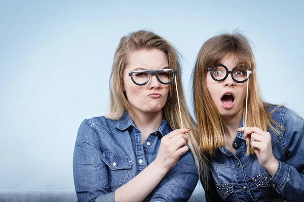 Two happy women holding fake eyeglasses on stick — Stock Photo, Image