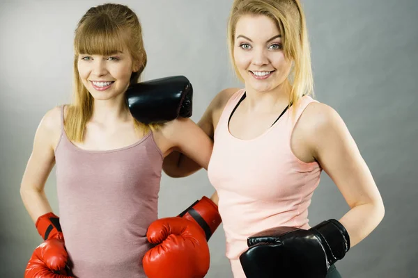 Two women friends wearing boxing gloves