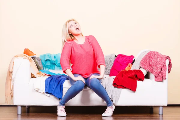 Woman does not know what to wear sitting on couch — Stock Photo, Image