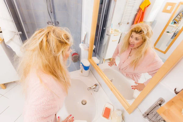 Woman looking at her very tangled blonde hair