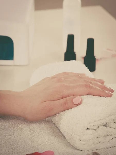 Woman hand on towel, next to manicure set