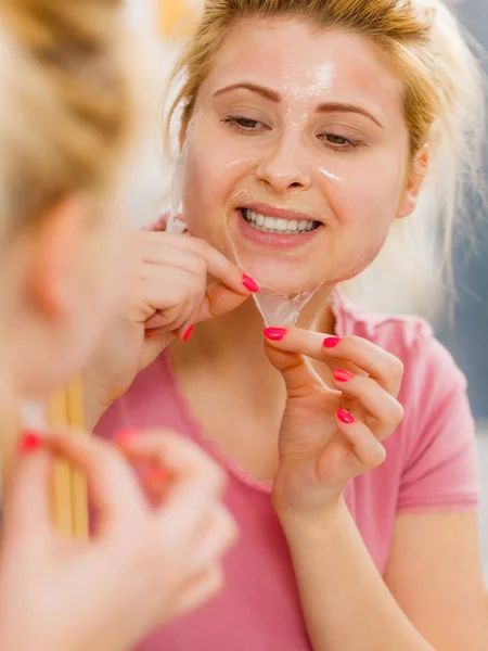 Woman peeling off gel mask from face — Stock Photo, Image