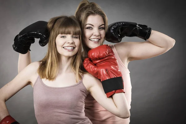 Two women friends wearing boxing gloves