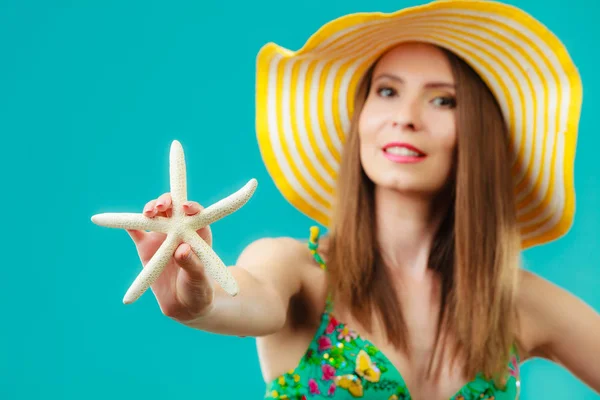 Woman in yellow hat holding white shell — Stock Photo, Image