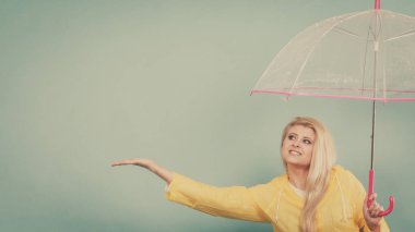 Hava kontrol şemsiye tutan yağmurluk giyen kadın