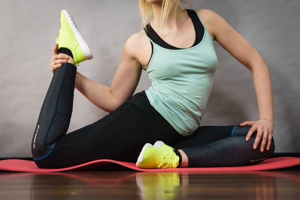 Vrouw in sportkleding benen rekken — Stockfoto