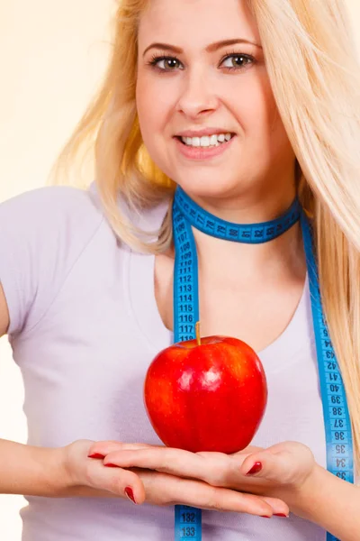 Woman with measuring tape around neck holding apple — Stock Photo, Image