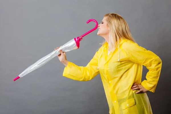 Happy woman wearing raincoat holding closed umbrella — Stock Photo, Image