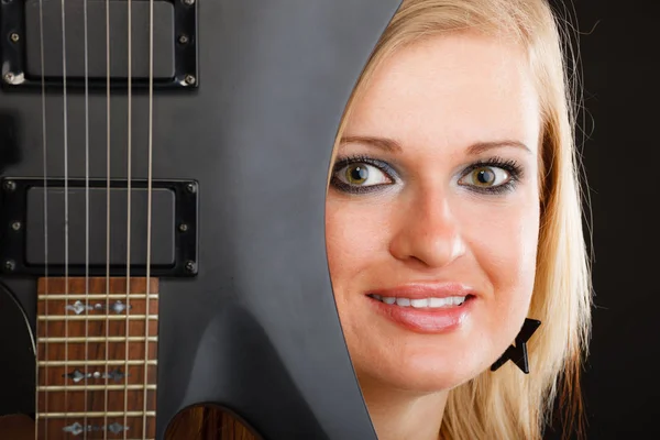 Blonde woman holding electric guitar, black background — Stock Photo, Image