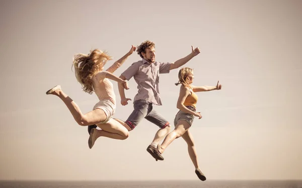 Carefree friends jumping by sea ocean. — Stock Photo, Image